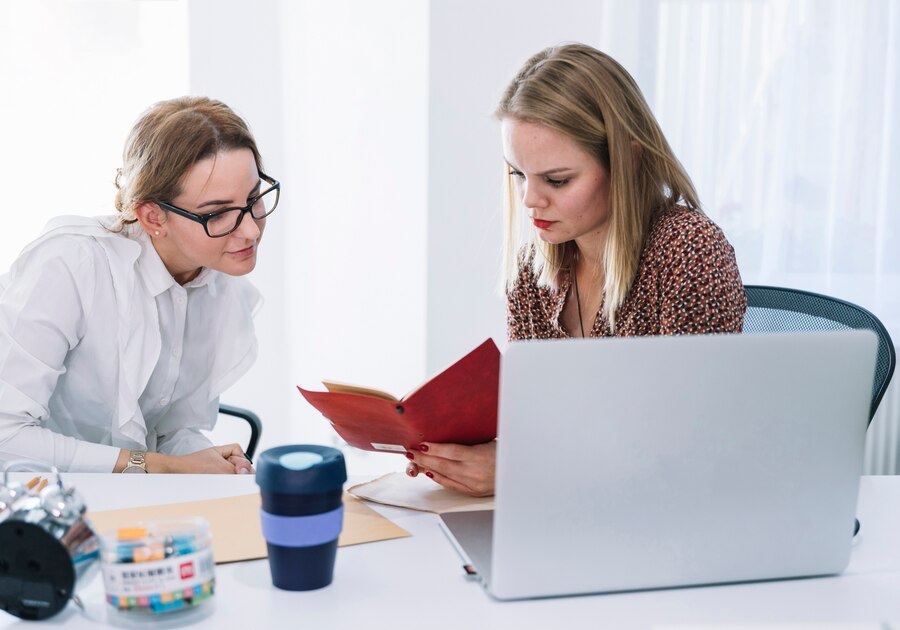 two female businesspeople reading diary office 23 2147955052